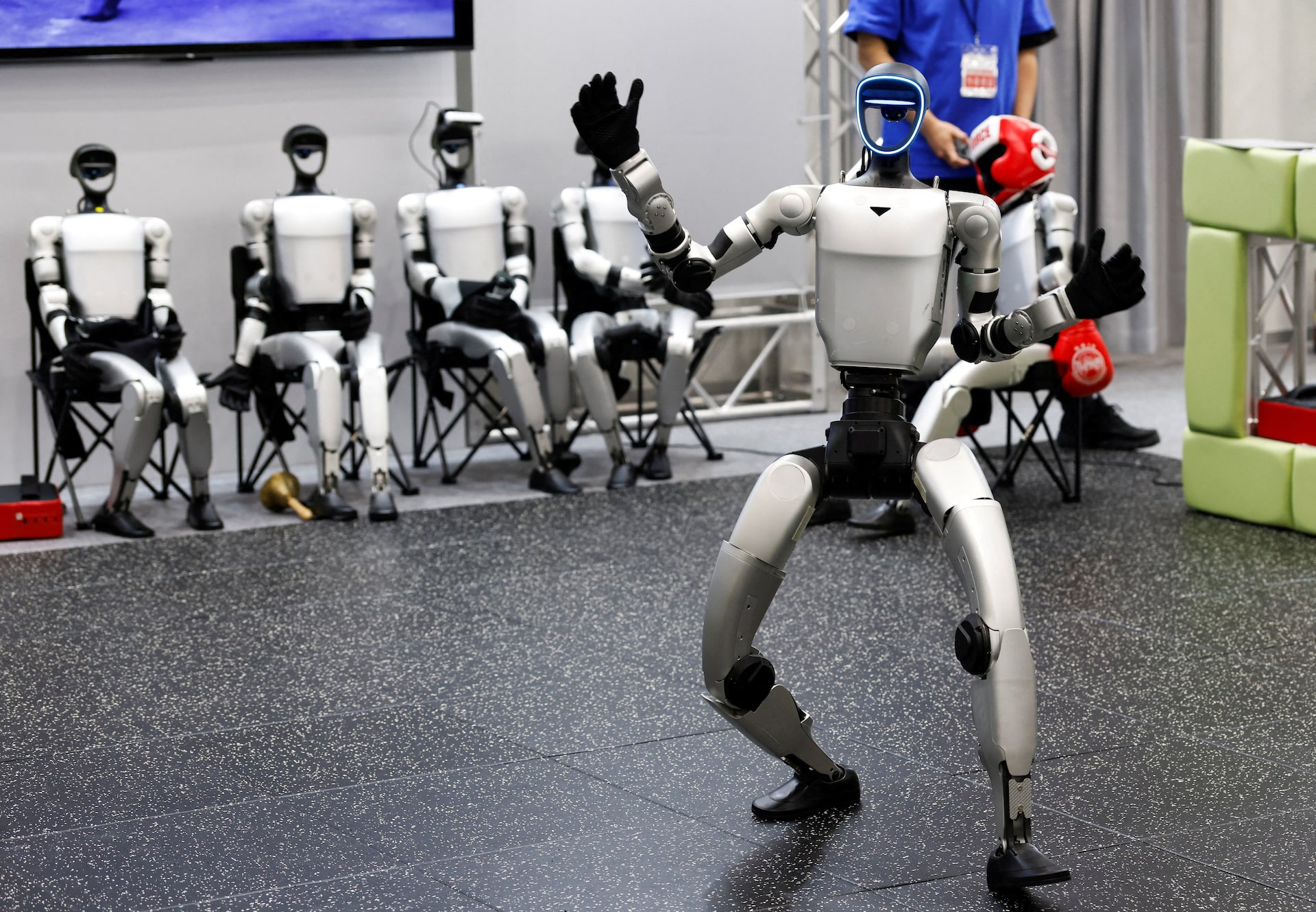 Unitree humanoid robots performing scripted demo at exhibition booth with operator present