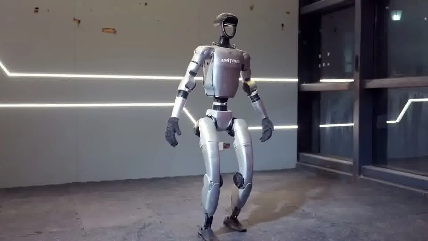 Unitree G1 humanoid robot in an active walking demonstration at an event venue showing bipedal locomotion in motion