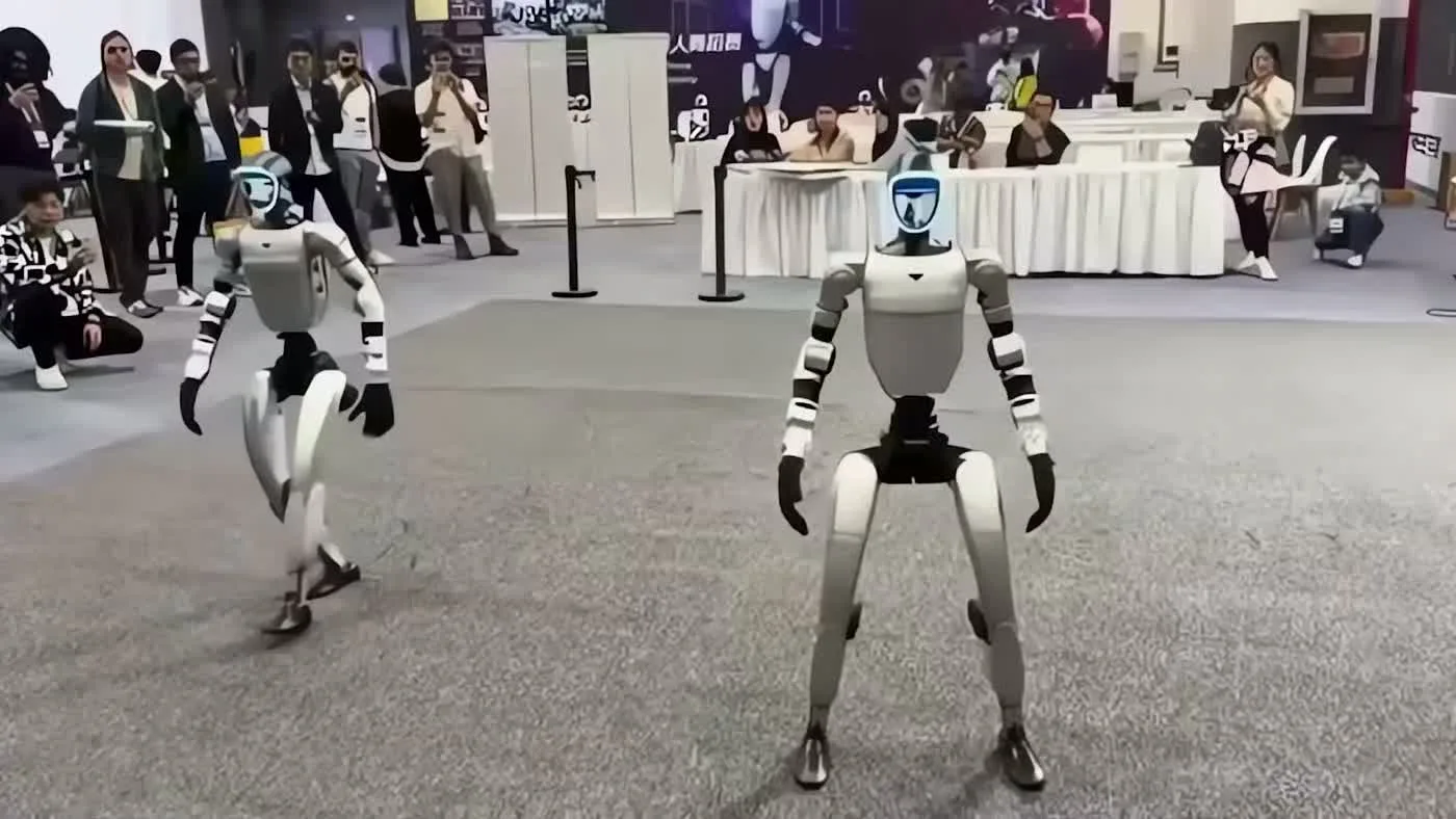 Unitree G1 humanoid robot in an indoor space being observed by visitors during a walkthrough session
