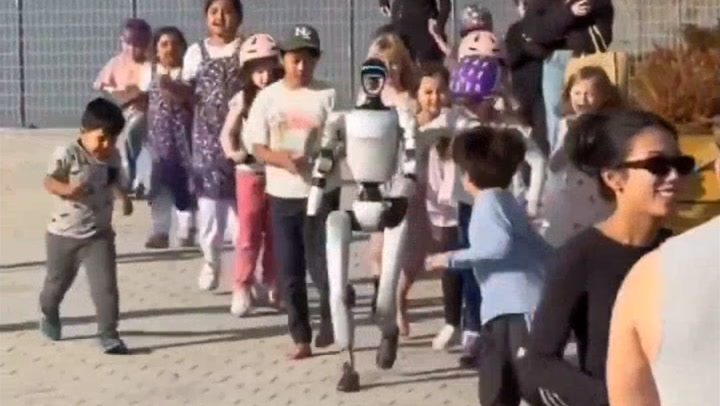 Humanoid robot running and playing with children draws social proof crowd of phones
