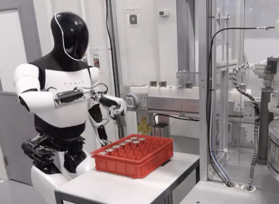 Tesla Optimus humanoid robot standing in facility demonstrating bipedal walking and manipulation