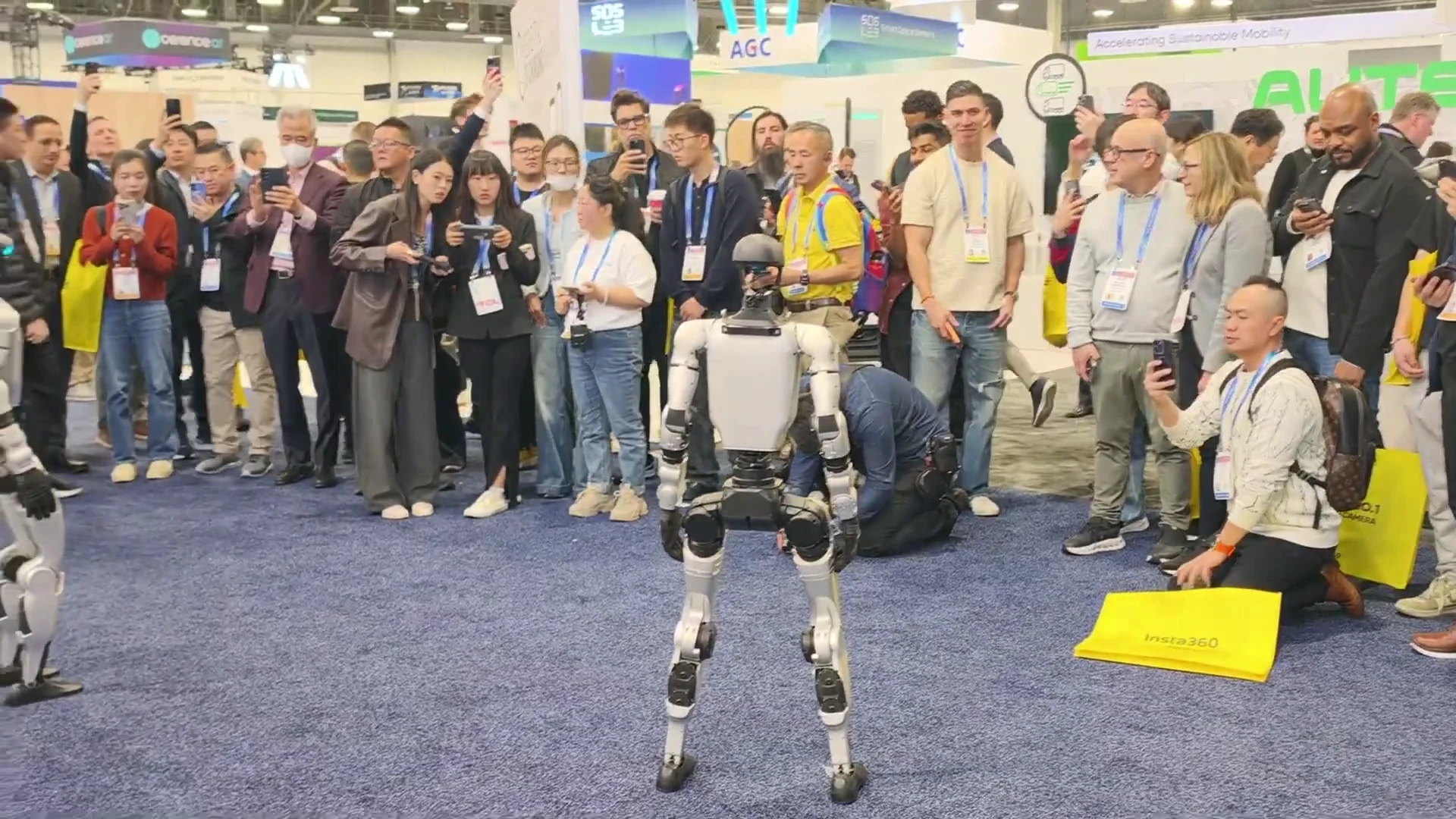 Two Unitree G1 humanoid robots running booth demo for crowd at CES 2026 trade show floor