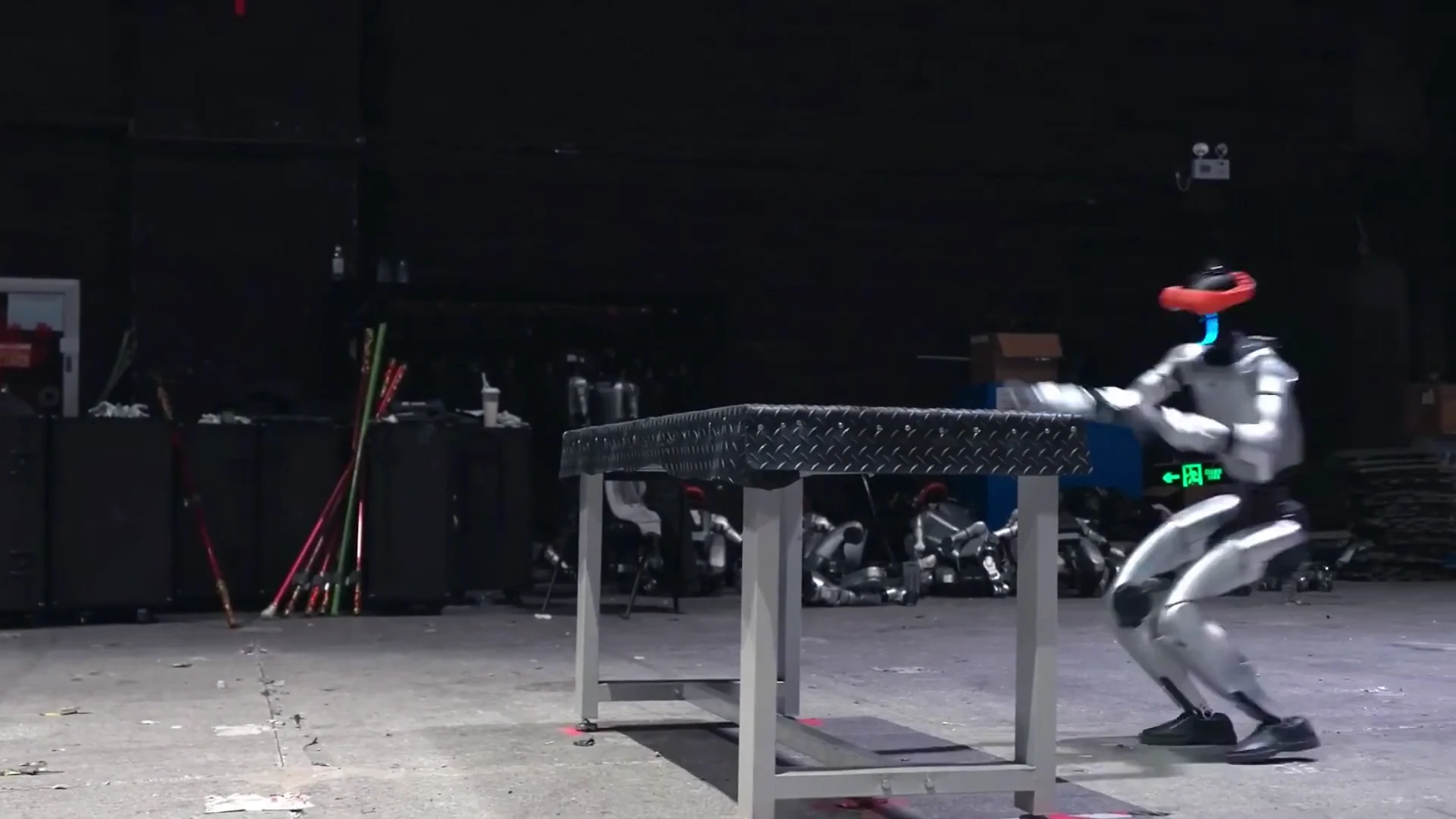 Unitree G1 humanoid robot warming up in indoor staging area before a scheduled exhibition demo