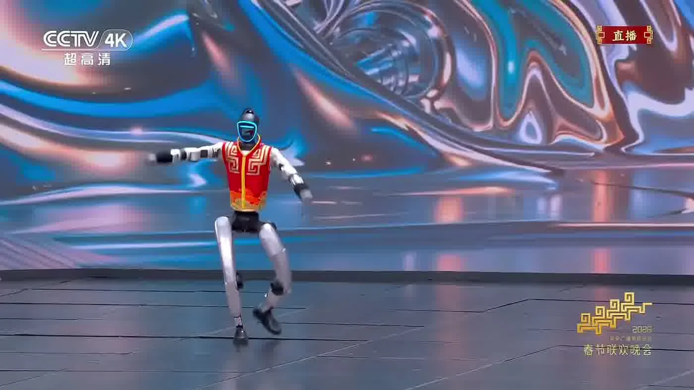 Unitree G1 humanoid robot performing a scripted gesture sequence at an event venue with event staff nearby