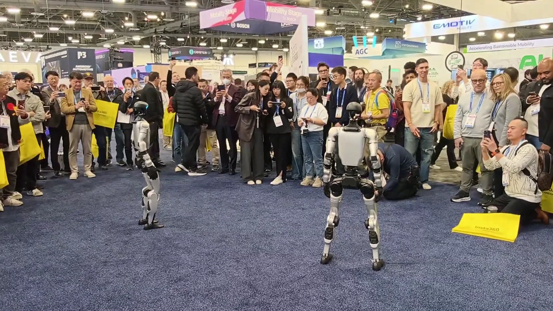 Two Unitree G1 robots on the CES 2026 trade show floor surrounded by a crowd of attendees