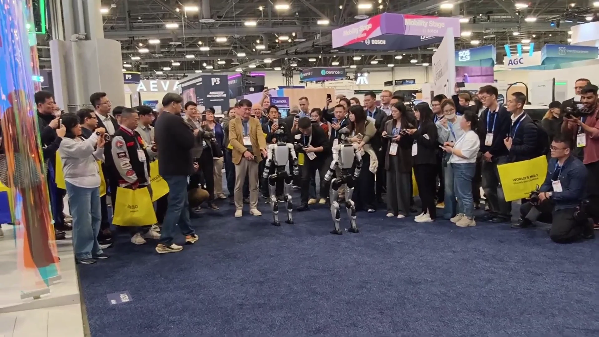 Two Unitree G1 humanoid robots positioned close together at a CES trade show booth in Las Vegas