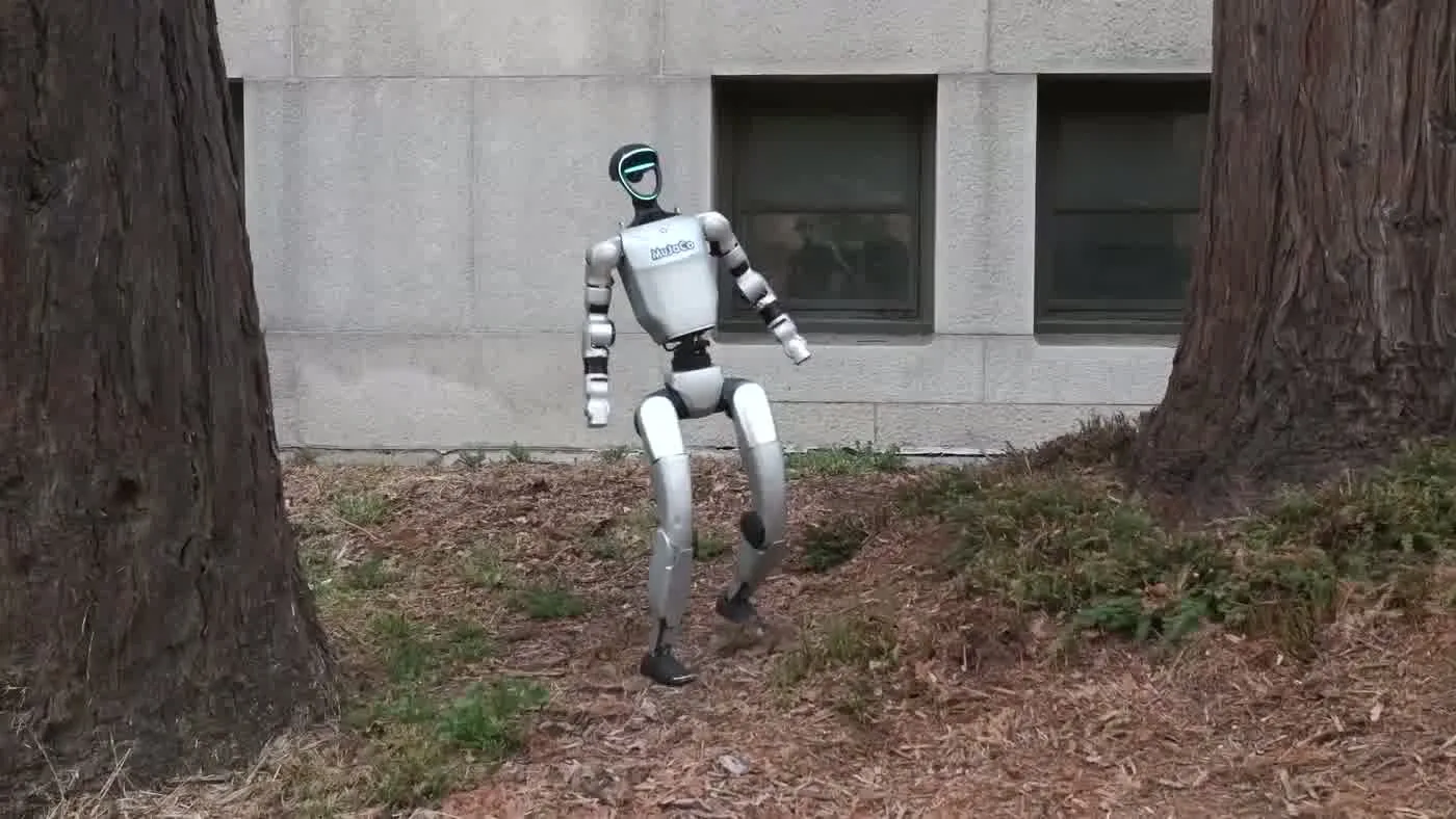 Unitree G1 humanoid robot walking toward camera during a staged product reveal at a corporate event