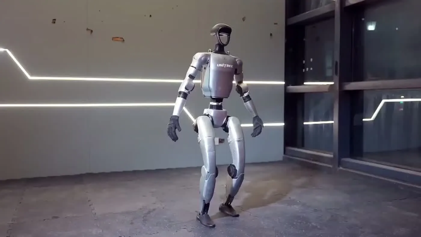 Unitree G1 humanoid robot standing upright in an indoor space with LED lighting, showing full body profile