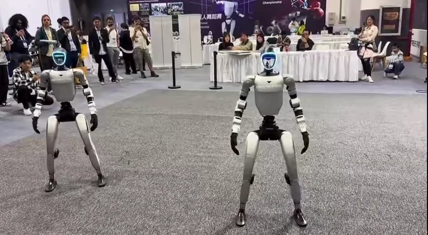 Two Unitree G1 humanoid robots performing a synchronized movement demonstration showcasing capability and agility