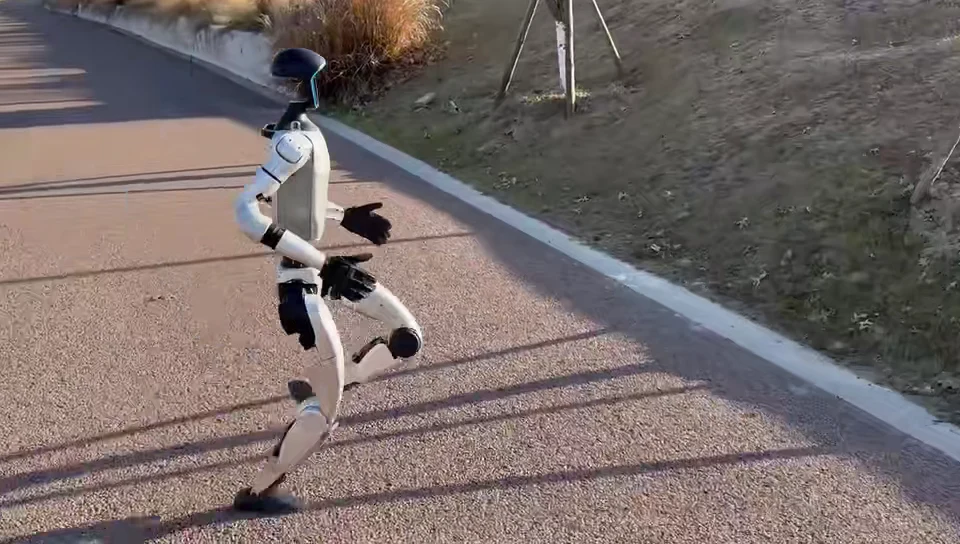Unitree G1 humanoid robot jogging outdoors on a paved path during a real-world mobility test