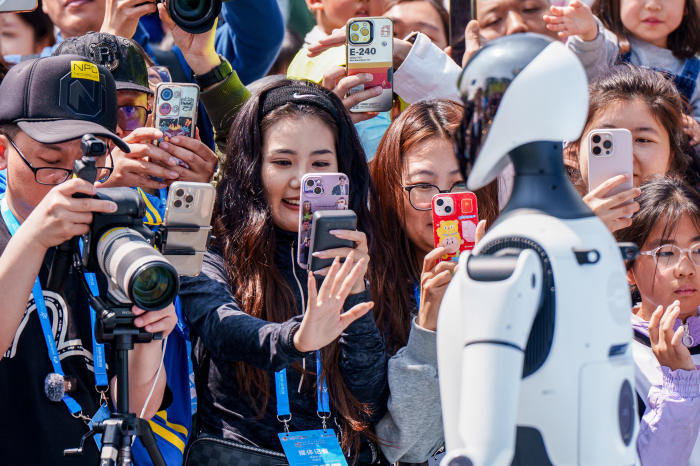 Crowd of people filming and watching humanoid robots at a public expo in China