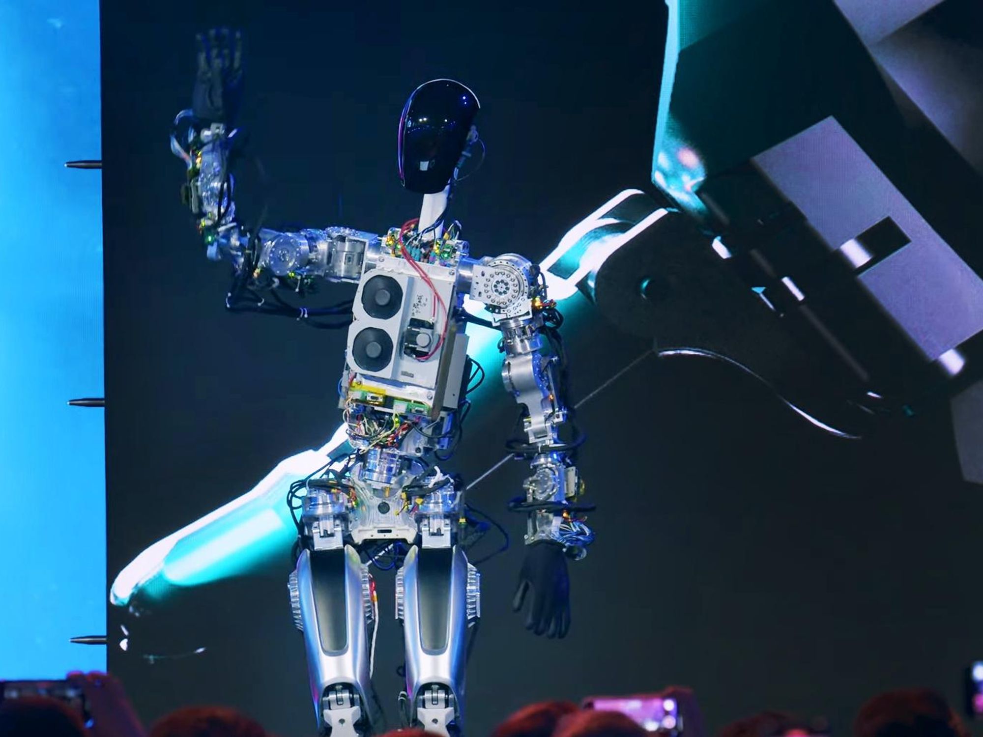 Tesla Optimus humanoid robot waving at audience from a stage during AI Day demo